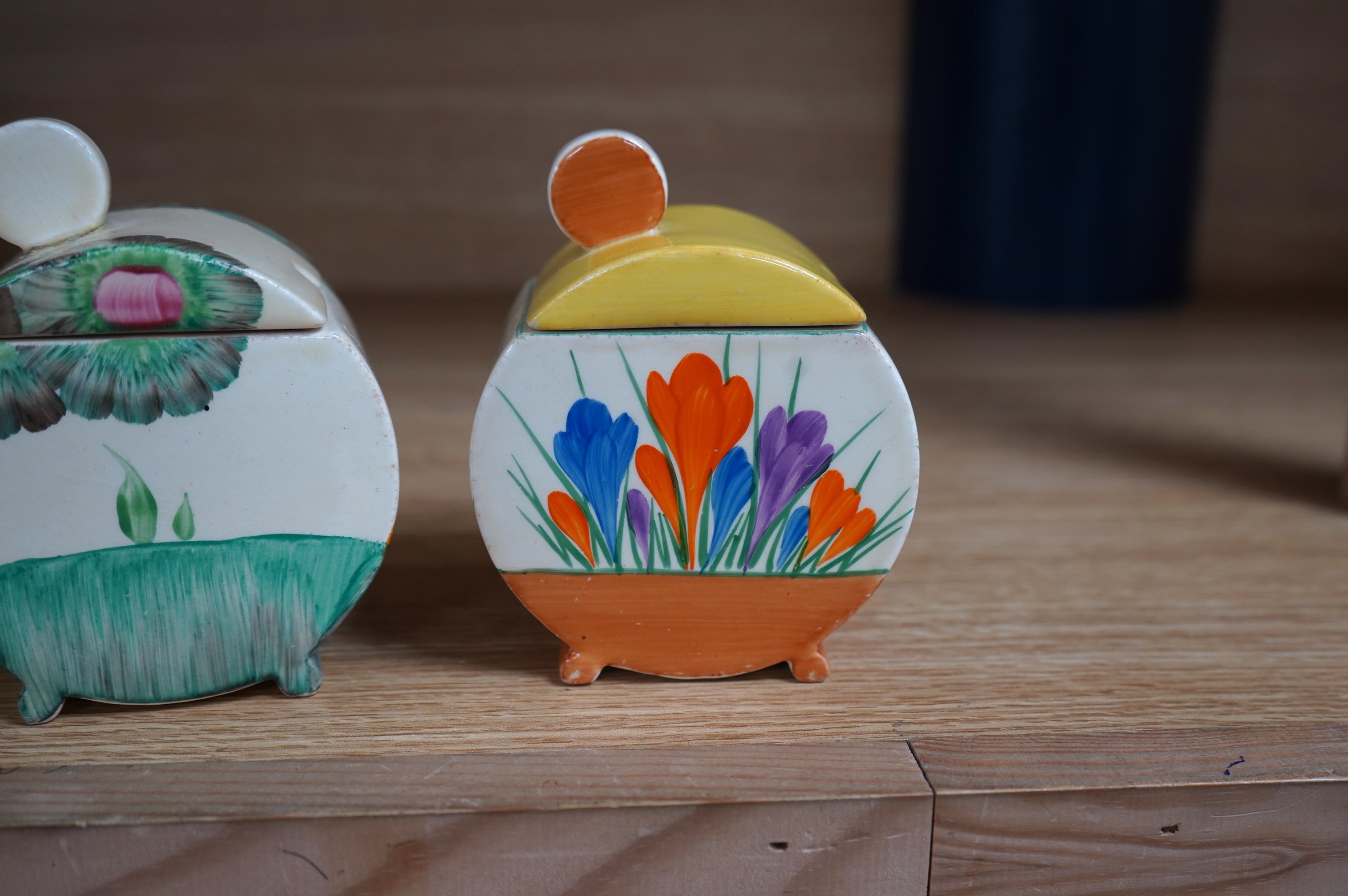 Two Clarice Cliff drum shaped preserve pots and covers, one in Crocus pattern and the other in Viscaria pattern. Condition - good